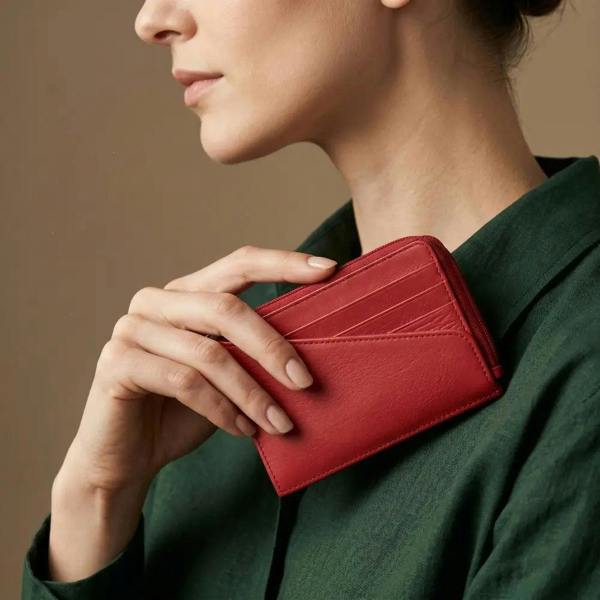 Person holding a red wallet against a neutral background
