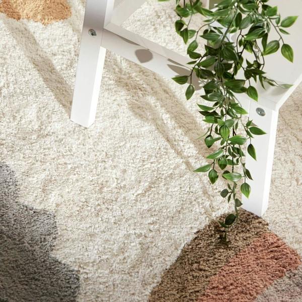 Close-up of a textured rug with a plant and chair leg.