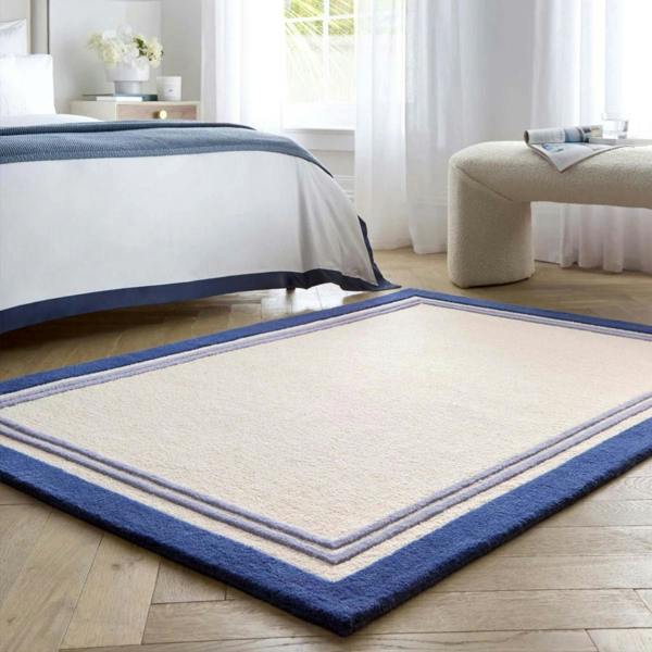 Beige rug with blue border in a bedroom setting