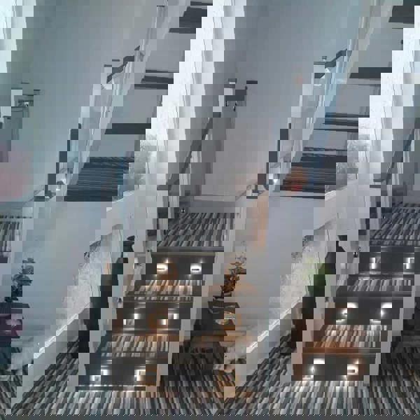 mini interior step light installed on a home stairway with striped carpet