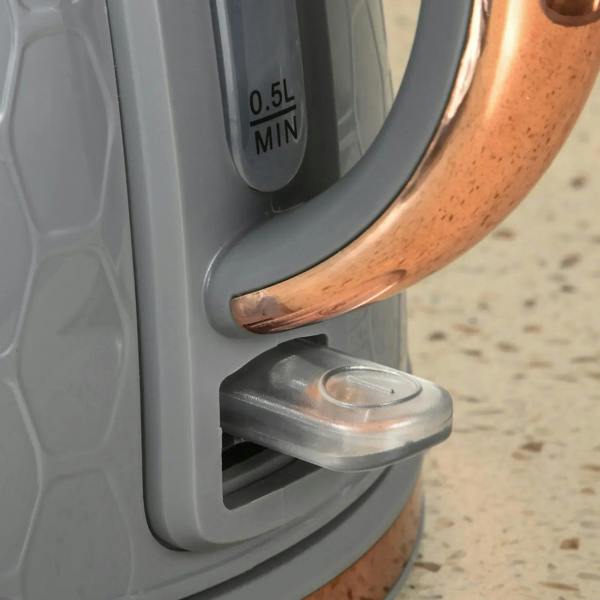 Grey electric kettle handle with rose-gold rim and water level markings on control panel