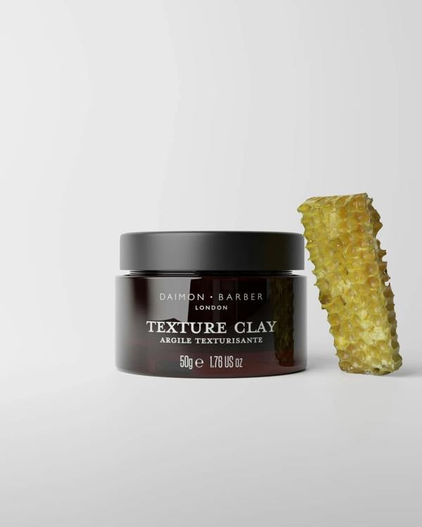 Jar of Daimon Barber Texture Clay 50g with a honeycomb next to it on a light gray background