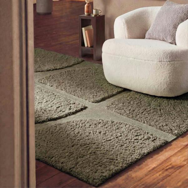 Green area rug on a wooden floor with a white sofa in the background