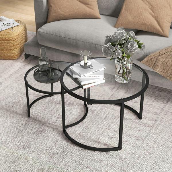 Black two-piece round coffee tables with glass tops and curved metal frames on carpet.