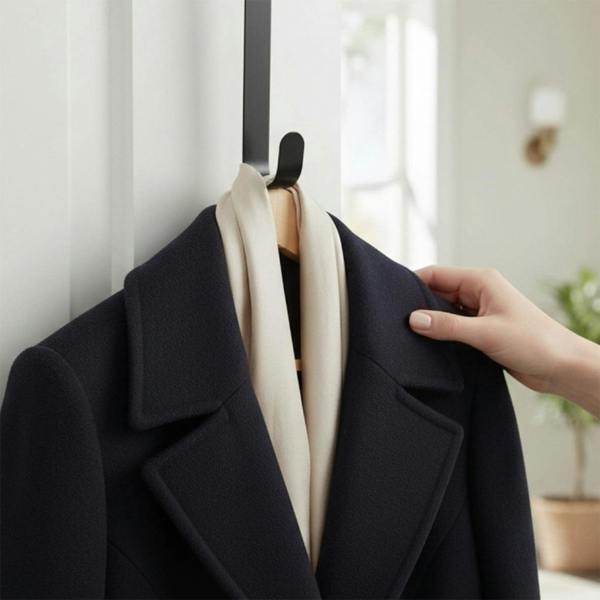 Navy colour coat with a cream scarf on a metal hook with a blurred indoor background