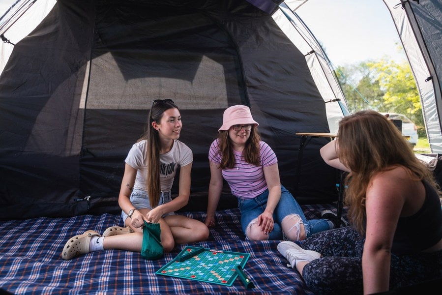 A group of young women chat inside the Stafford 6.0 family tent by OLPRO x Ed Stafford