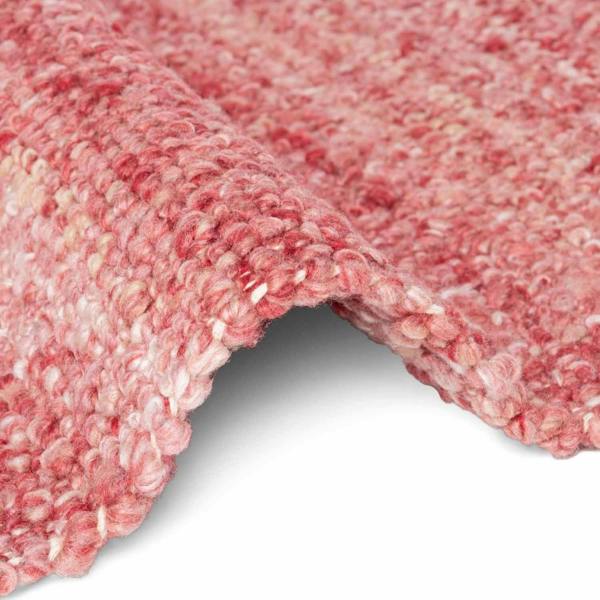 Close-up of a textured pink carpet corner on a white background