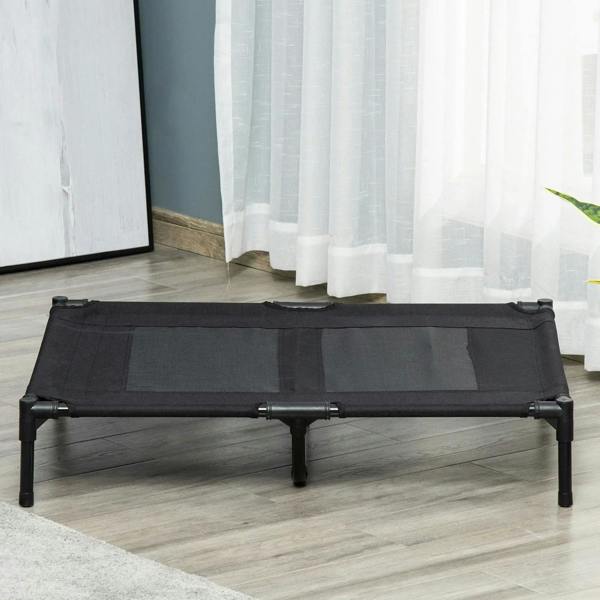 Black raised pet cot with mesh panels and four metal legs on an indoor floor