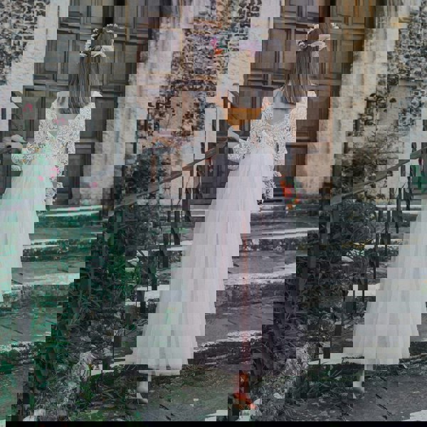 girl in a white lace dress standing on steps outside a stone building.