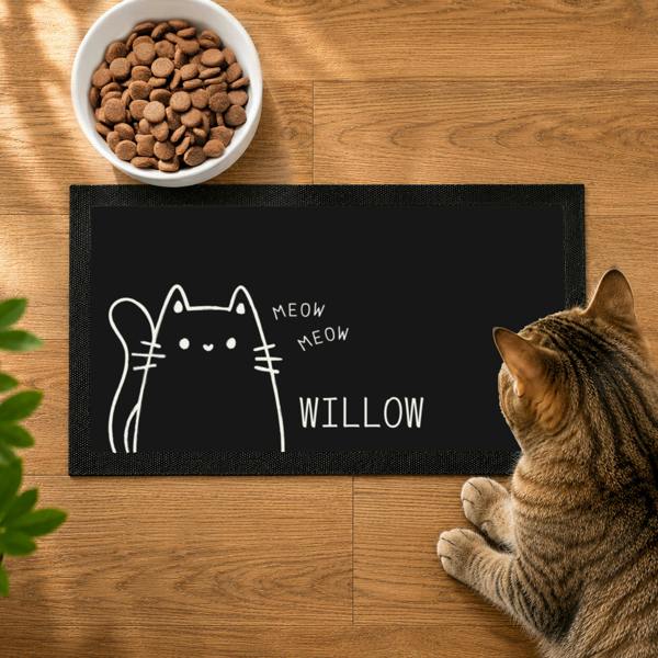 Personalised black cat bowl mat featuring a white outline illustration of a cat and the name WILLOW.