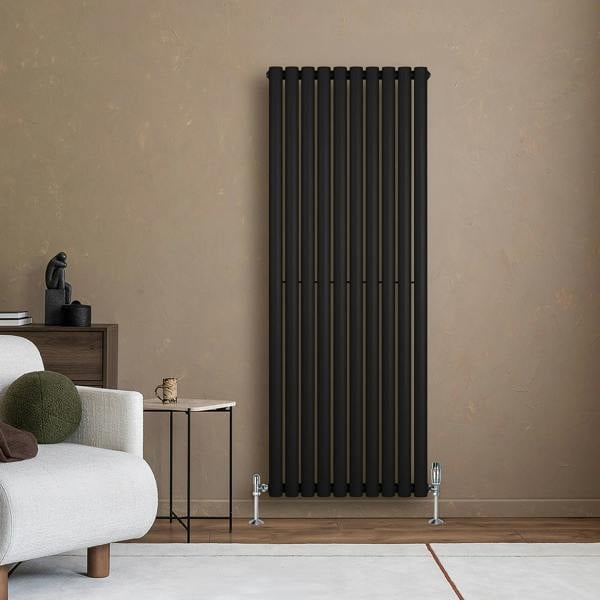 Sleek black oval single column radiator mounted on a textured beige wall, complemented by stylish valves and modern decor elements