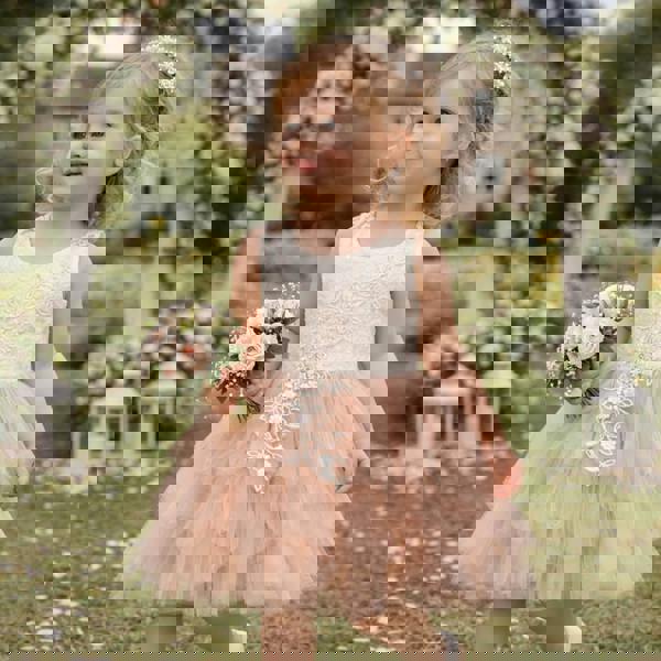 Young girl in a floral dress holding flowers in a garden setting with floral arches.