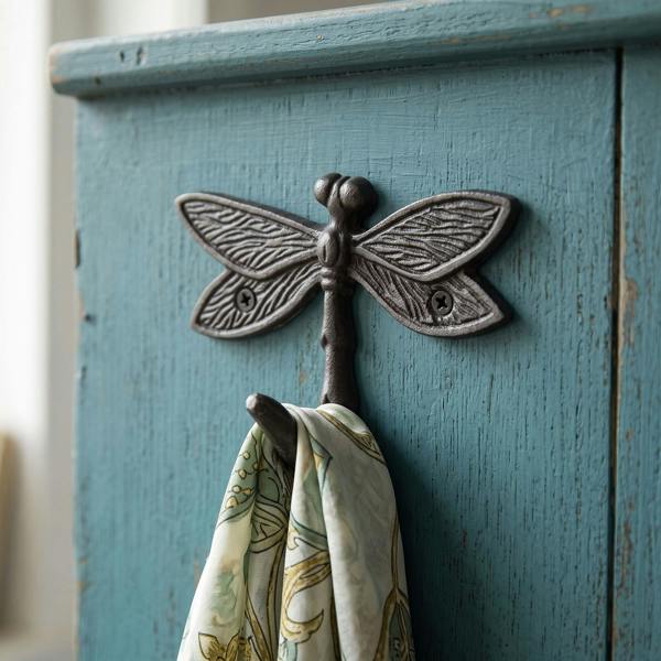 Close-up of cast iron dragonfly coat hook mounted on a rustic wall, highlighting detailed dragonfly design and sturdy construction, with a soft scarf hanging.