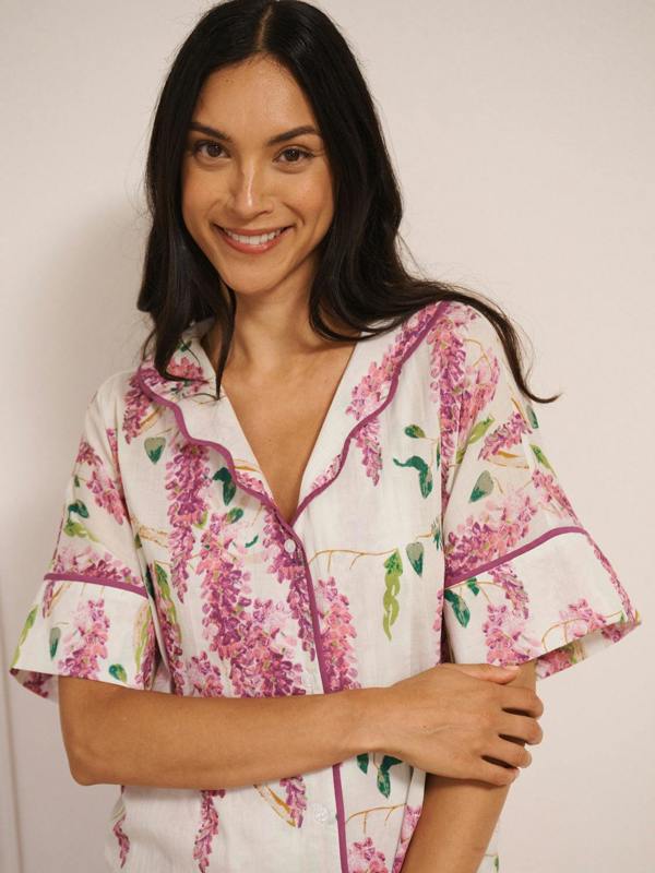 Model wearing white cotton voile oversized shortie pyjamas with pink wisteria print, short-sleeve shirt and elasticated waist shorts with pockets. detail