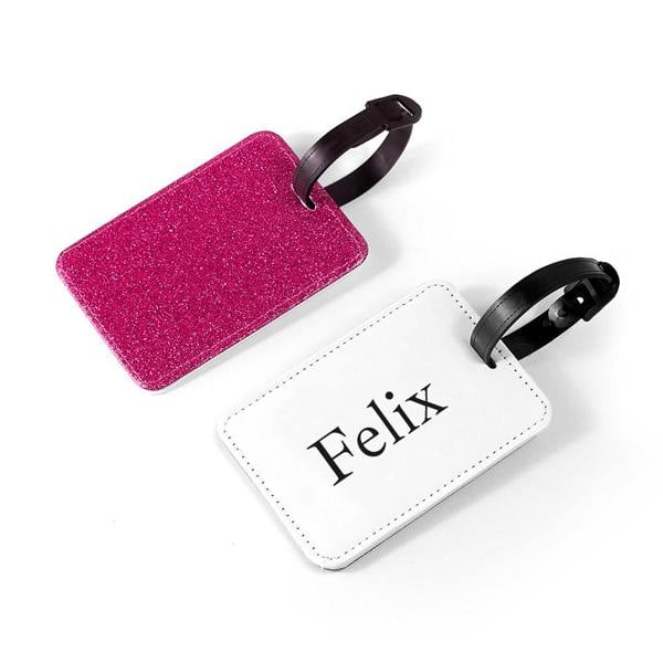Personalised pink glitter school bag tag with a black strap, showing the white reverse side printed with the name Felix in a serif font.