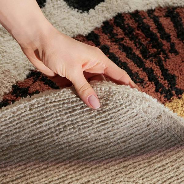 Hand touching a textured surface on a patterned rug