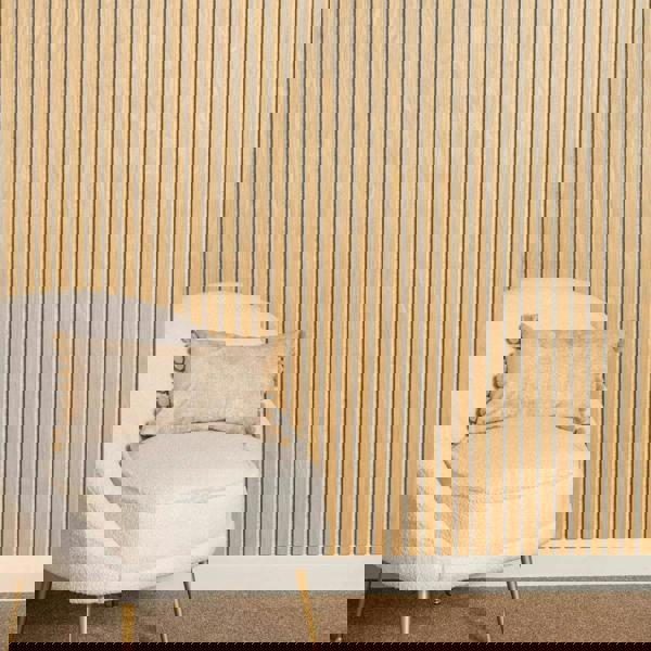Beige chair with a decorative pillow against a oak on a light grey wall.