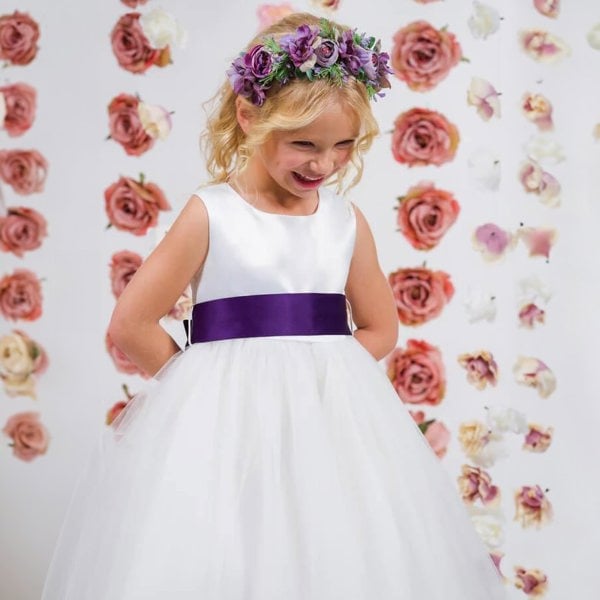 Young girl in a show dress with a purple sash and floral hairband