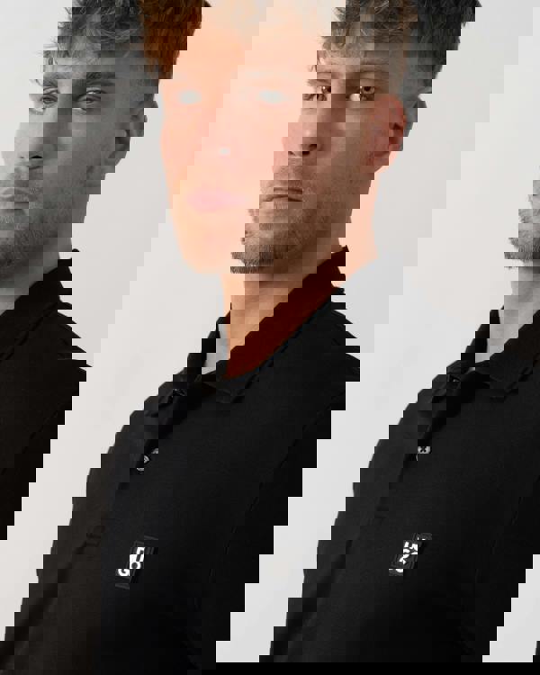 Model wearing HUGO Dinote Mens Long Sleeve Polo Shirt in Black 001 - Neckline Detail