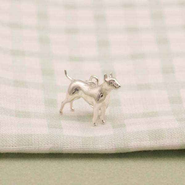 Silver English Bull Terrier dog-shaped earring on a textured white fabric background
