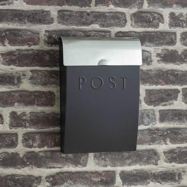 A dark carbon grey metal post box with a silver galvanised lid and "POST" embossed on the front, mounted on a brick wall.