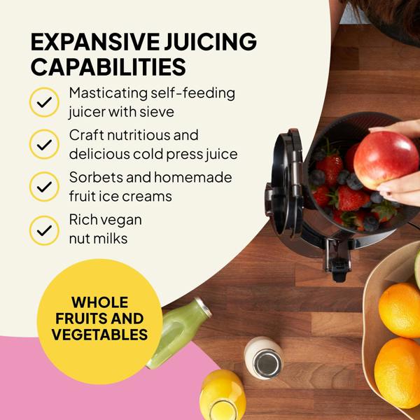 A person places an apple into the Fridja Citrus & Juice Duo—f800 Automatic Citrus Juicer & f2500 Self-Feeding Juicer—surrounded by berries, assorted fruits, juice bottles, and feature text on a wooden and pink background.