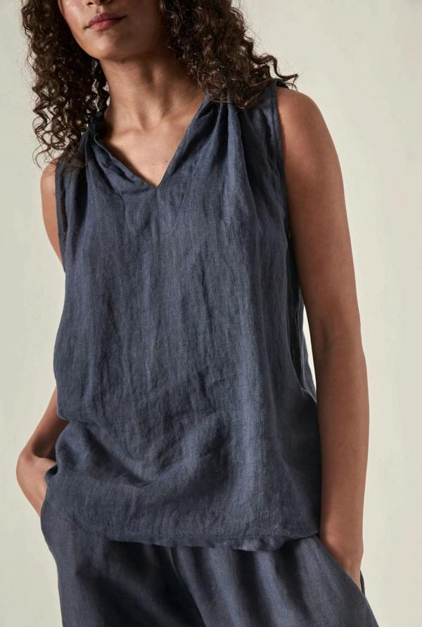 Woman wearing a sleeveless navy linen top against soft beige background