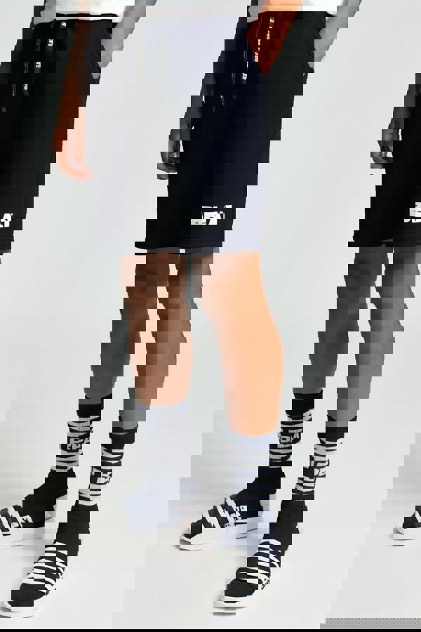 Person wearing navy shorts with 'BEAT' branding, matching socks, and Adidas shoes on a white background