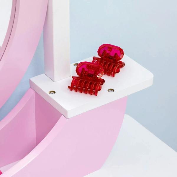 Pink kids dressing table set shelf with red clip accessories on white tabletop