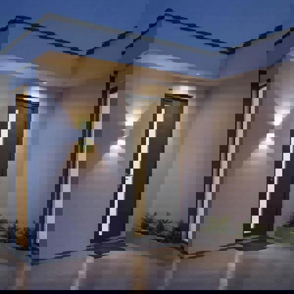 white up and down outside light mounted on the wall next to the front door of a modern house 