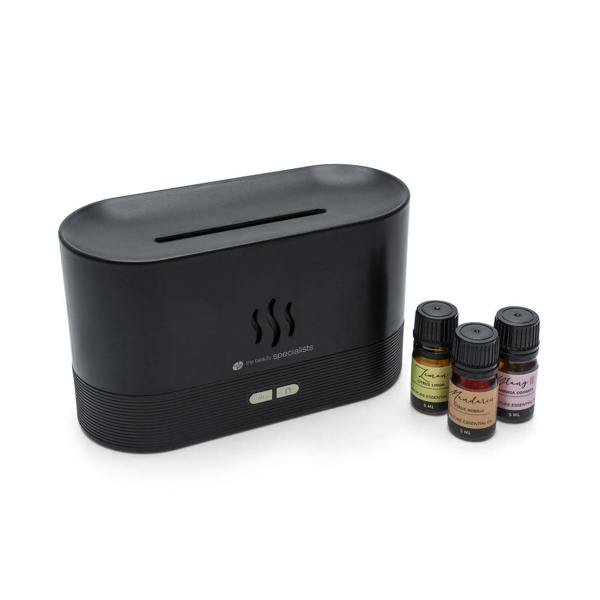 The Rio ALTA Aroma Diffuser, Humidifier and Night-light in black sits beside three colorful essential oil bottles, all displayed against a white background.