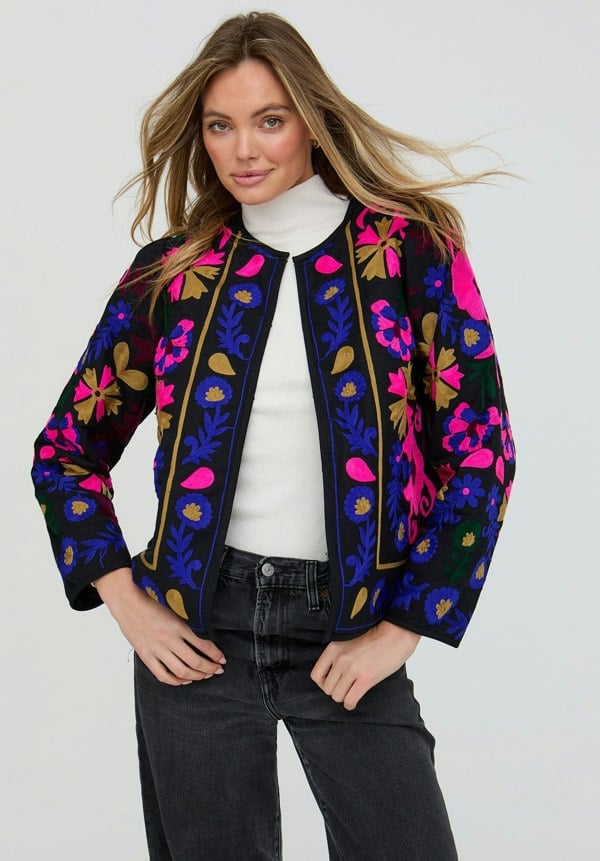 Woman wearing a colorful floral jacket on a white background