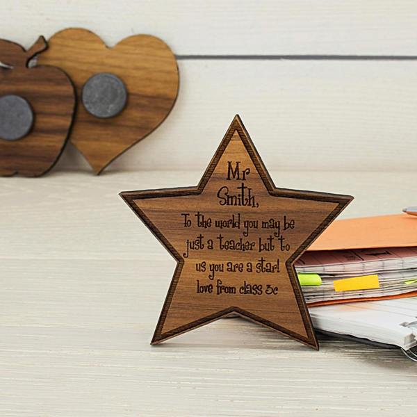 Custom engraved walnut star teacher magnet standing upright with apple and heart wooden magnets in the background.