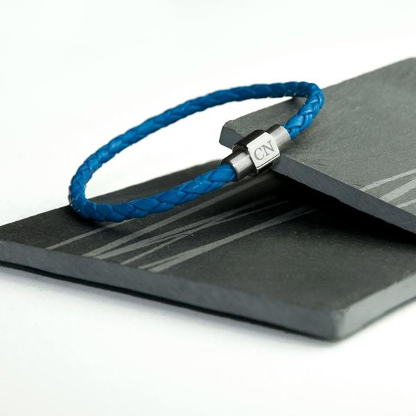 A vibrant cobalt blue braided men's leather lifestyle bracelet displaying a steel magnetic metal clasp engraved with the initials CN.