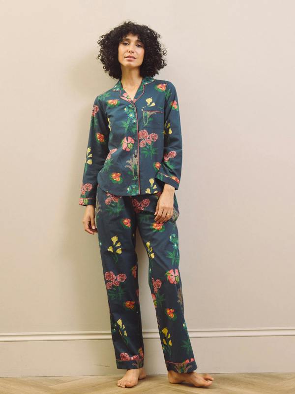 Woman wearing a navy blue floral pyjama set against a plain background