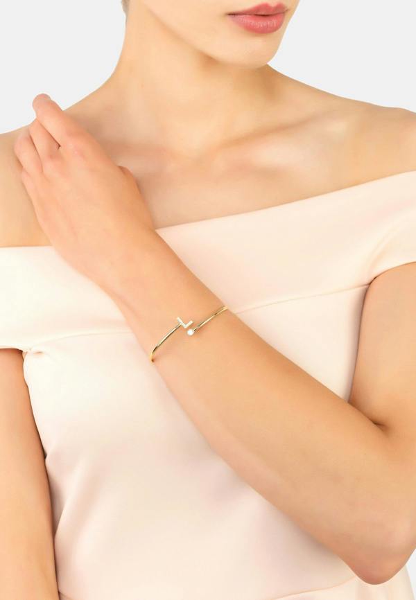 Woman wearing a delicate gold bracelet on a light background