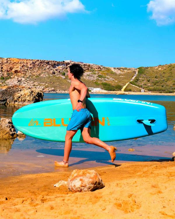 Man running on the beach with a  Blue Lagoon 10' Lite Bluefin sup paddle board 