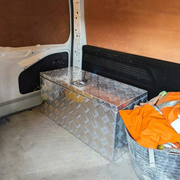Extra large 102L aluminum tool box with a diamond plate finish, placed in a van, surrounded by tools and an orange blanket