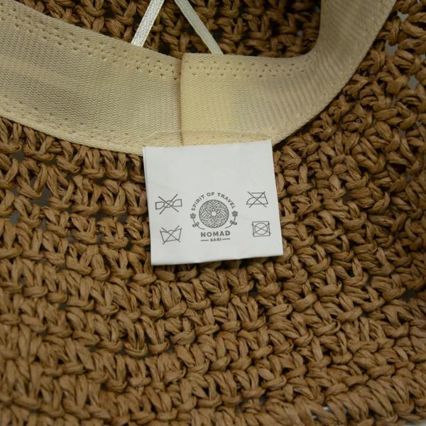 Straw hat interior close-up showing light ribbon band and brand swing tag