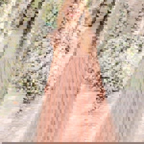 Young girl in a pink dress standing in front of floral decorations