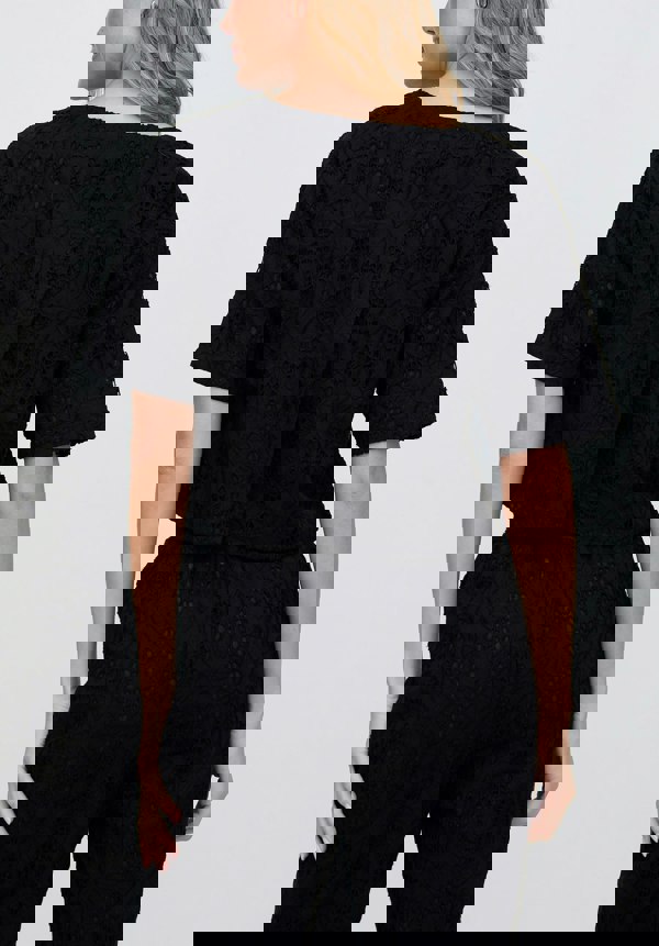 Person wearing a black textured outfit on a plain background