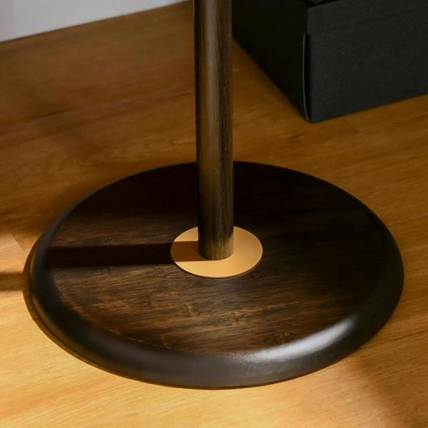 Freestanding coat rack stand with round dark base and vertical pole with gold cap