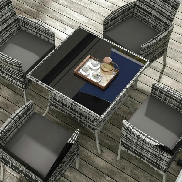 Top view of grey rattan dining table with glass surface and four padded chairs