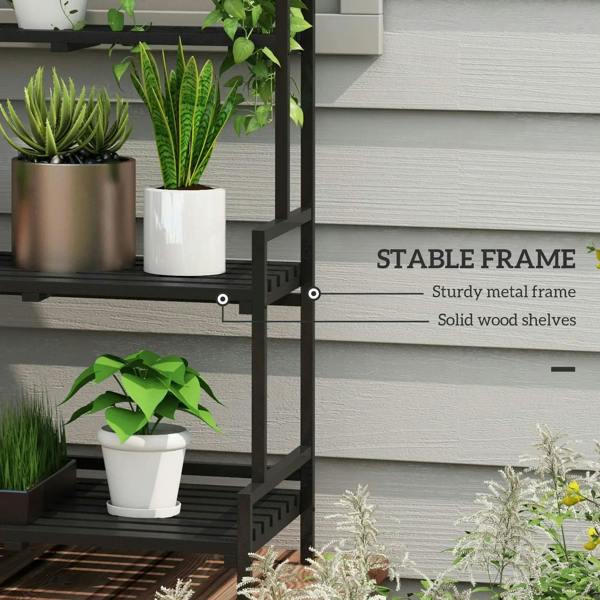 Black metal plant rack with three shelves and hanging hooks beside potted plants