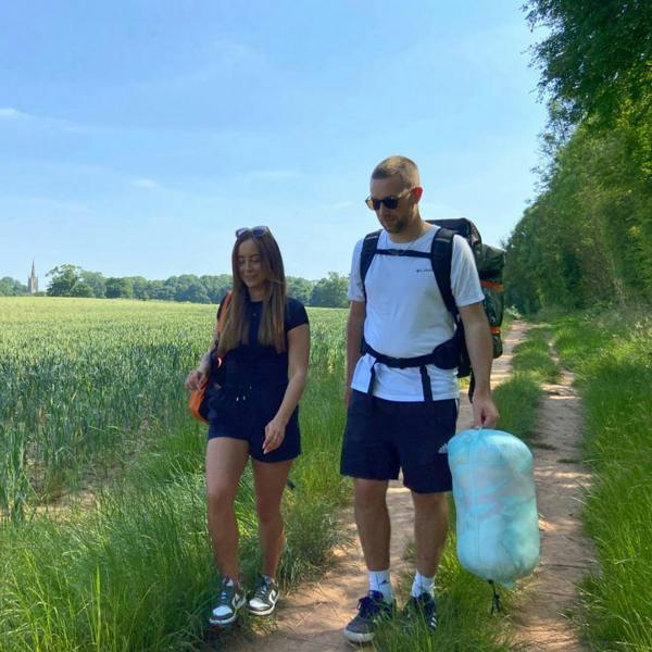 A young couple out walking with a rucksack and carrying an Insulated Outdoor Blanko. imageset:Tonal Tree Tops