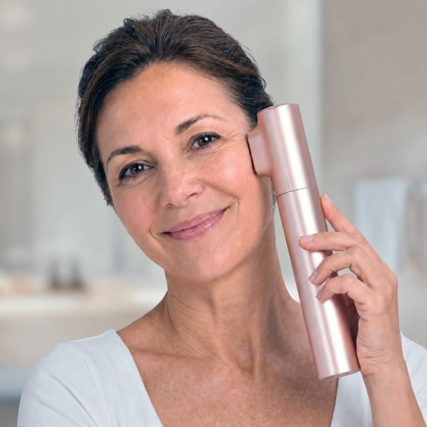 Woman holding the Innocera Platinum skincare device against her cheek during an at-home facial treatment.