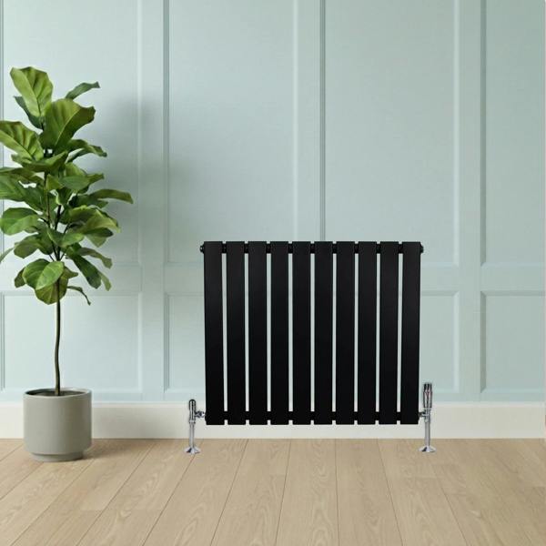 Flat black single column radiator, 600 x 700mm, featuring sleek vertical slats, positioned against a light blue wall with a plant nearby
