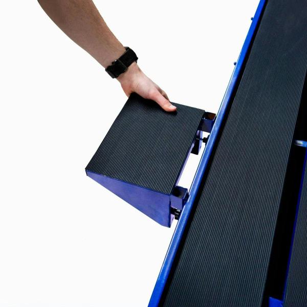 Hand adjusting the textured black cutting platform on a blue wet tile cutter bench, showcasing its adjustable features and sturdy design