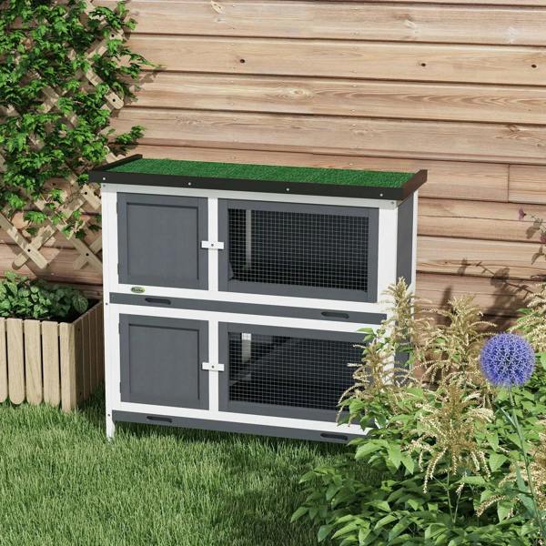 Outdoor grey two-tier rabbit hutch with green roof cover and wire mesh windows