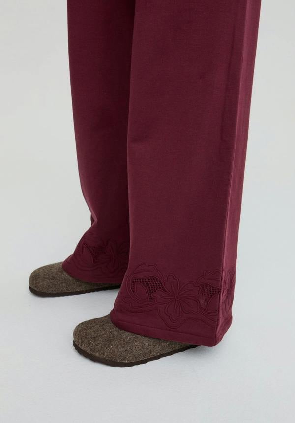 Maroon pants with brown slippers on a white background